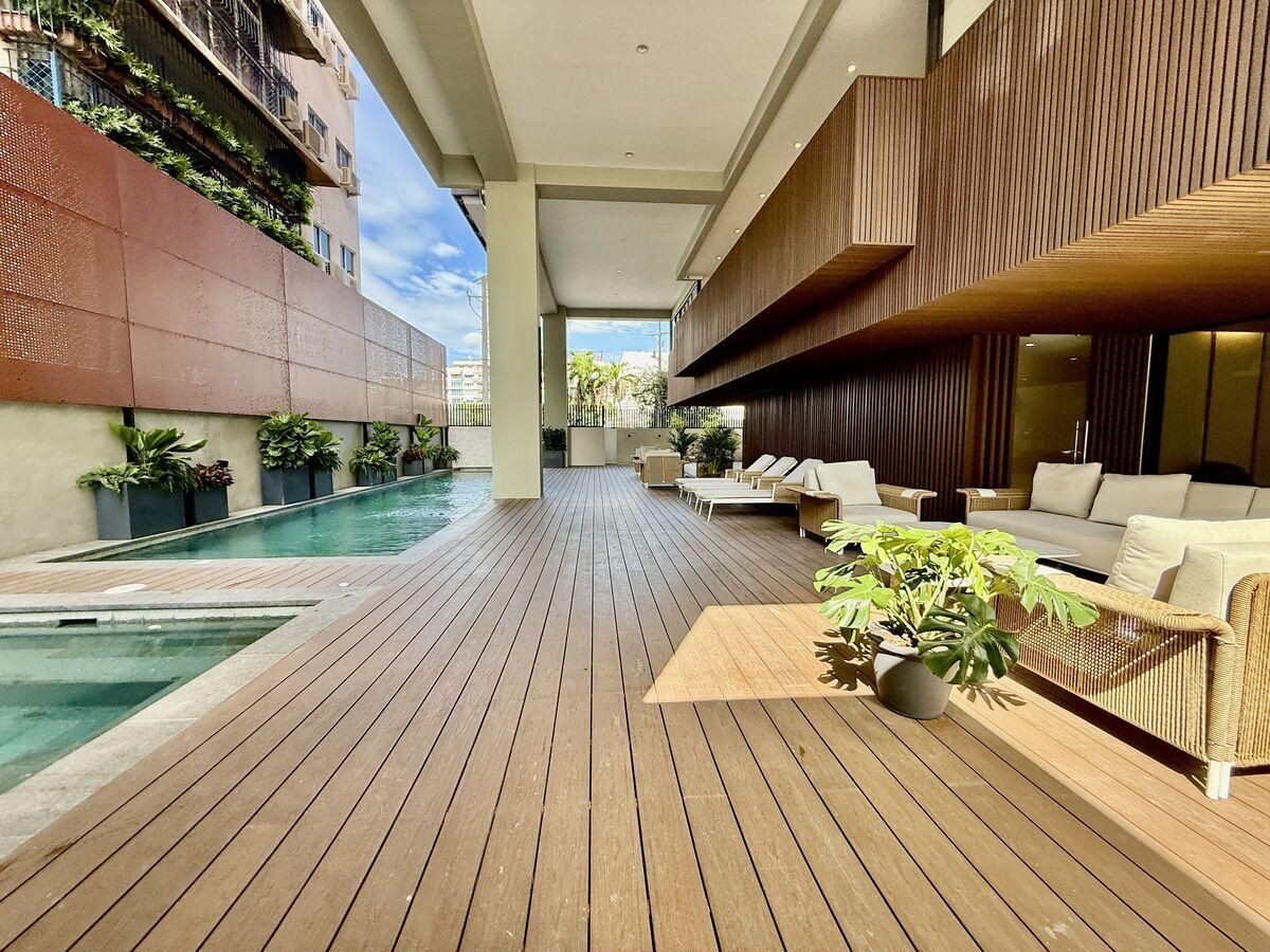Piscina del edificio con deck de madera y área lounge techada